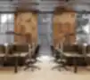 Šiuolaikinė biuro darbo erdvė su ergonomiškais stalais, privatumo panelėmis, reguliuojamomis juodomis biuro kėdėmis ir dideliais industrinio stiliaus langais su perforuotomis medinėmis sienų plokštėmis.