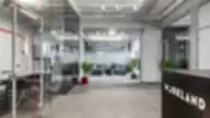 Modernaus coworking biuro erdvė su stiklinėmis pertvaromis, žaliosiomis sofos zonomis ir priekyje matoma „Workland“ registratūra.