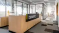 Modernus „Dematic“ biuro registratūros stalas su medžio apdaila ir stiklinėmis pertvaromis.