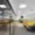 Modernus DHL Lietuva atviro plano biuras su eilėmis darbo stalų, geltonomis akustinėmis pertvaromis ir stiklinėmis kabinomis, kylančiomis iš pilkos ir geltonos kiliminės dangos, tarpai atskirti juodos metalinės grotelės panelėmis.