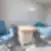 Nordclinic konsultacijų kabinetas Kaune su lenktu mediniu stalu, mėlynomis kėdėmis ir stovinčiu šviestuvu šviesioje patalpoje.