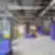 Atvira ir spalvinga WORKLAND | VILNIUS, BURĖS bendradarbiavimo erdvė su violetiniais stulpais, pilkais kilimais, geltonomis lentynomis ir moderniais, moduliniais violetinės spalvos minkštais sėdimaisiais baldais.