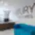 Modernus „Nextury Ventures“ registratūros interjeras su mediniu lenktu stalu, mėlyna sofa ir logotipu ant baltos sienos.