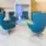 Moderni Nordclinic klinikos laukiamoji erdvė su ryškiai mėlynomis kėdėmis, stiklo staliuku ir šiuolaikiniu interjeru.