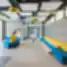 Balsių mokyklos moderni poilsio zona su spalvingais baldais, geometriniais lubų elementais ir dekoruota siena.