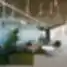 „Helis“ biuro poilsio zona su sofa, moderniu apšvietimu, stiklo pertvaromis ir dirbtinės žolės grindų akcentais.