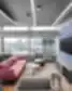 Modern office lounge with a pink sofa, grey seating, round coffee tables, and a blue acoustic wall with a mounted TV.