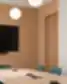 Meeting room interior detail with a wooden conference table, green chairs, a wall-mounted screen, and pendant lights.