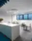 Moderni „New Crush“ biuro poilsio zona su balta virtuvės sala, LED žiediniu šviestuvu, mėlynomis grindimis ir stalo zona su kėdėmis