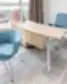 Modernus Nordclinic gydytojo kabinetas Kaune su mėlynomis kėdėmis, lenktu mediniu stalu ir miesto panorama pro langą.