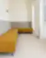 Rail holding poilsio zona su kampine moduline sofa pilkos ir garstyčių geltonumo spalvų, prie langų, baltos sienos ir sieniniai prožektoriai.
