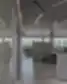 Atviro plano biuro erdvė su darbo vietomis ir betoninėmis pertvaromis prie langų.