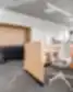 „Dematic“ biuro darbo vietos su medinėmis pertvaromis, ergonominėmis kėdėmis ir integruota virtuvėle.