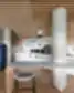 Moderni biuro virtuvė su baltomis spintelėmis, medžio apdaila, mėlynu retro stiliaus šaldytuvu ir aukštu baru su kėdėmis.