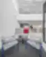 Šiuolaikiškas Hollister biuro priimamasis su dviem pilkomis kėdėmis mėlynais rėmais, apvaliu juodu staliuku ir foniniame plane matomu registratūros stalu su raudonu logotipu.
