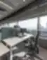 Modernus biuro stalas su dviem monitoriais, ergonomine kėde ir panoraminiu vaizdu pro langą į miesto dangoraižius.
