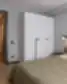 Modernus miegamasis su dvigule lova, balta spinta ir švelniomis žemės spalvų detalėmis Balcia Residence apartamentuose.