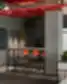 Emergn biuro poilsio ir kavos zona su baro tipo staliuku, oranžiniais akcentais ir žalumos elementais
