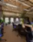 Co-working “Magnēts” interjeras su mediniais stalais, ergonominėmis juodomis ir mėlynomis kėdėmis, augalais ant stalų, aukštomis lubomis bei matomomis konstrukcijomis ir ortakių sistema.
