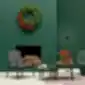 Modern lounge area with an armchair, side tables, and a Christmas wreath on a green wall.