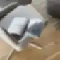 Šviesi Coco Swivel kėdė su atverstu žurnalu ant sėdynės, pastatyta ant medinių grindų