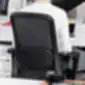Tinklelinis ergonomiškos kėdės atlošas su sėdinčiu žmogumi.