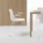 Balta Varya High VAR0079 kėdė su porankiais šalia medinio valgomojo stalo minimalistiniame interjere, INCLASS.
